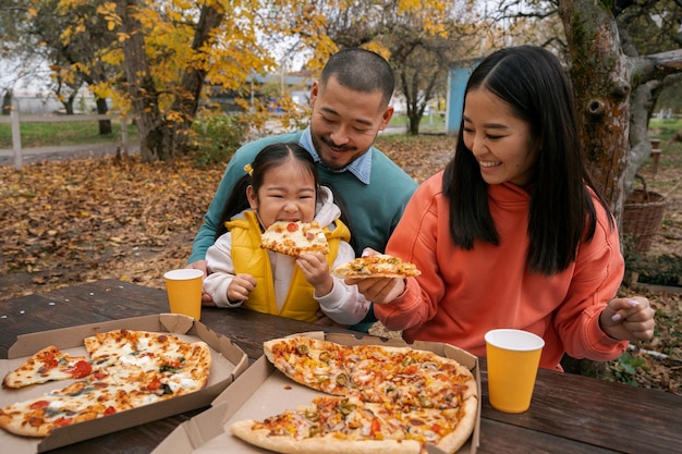 Free photo medium shot smiley family with delicious pizza