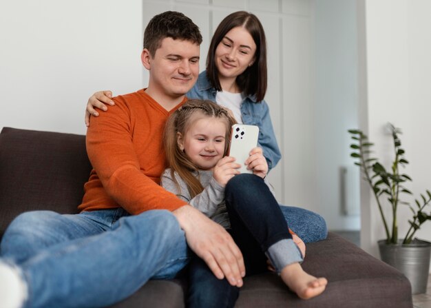 Medium shot smiley family with phone