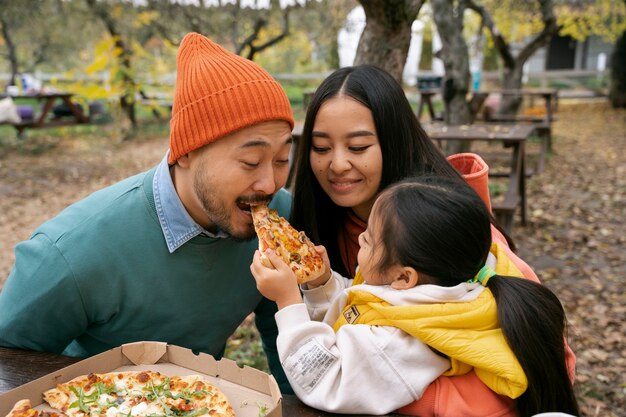 Free photo medium shot smiley family with pizza