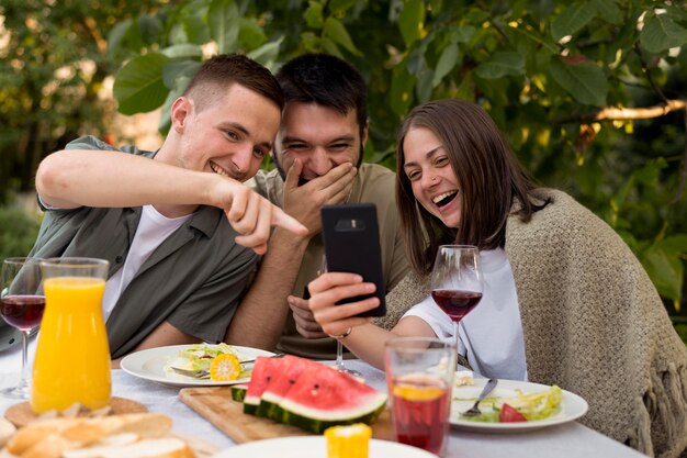 Medium shot smiley friends looking at phone