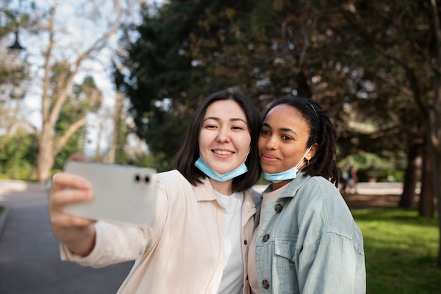 Free Photo medium shot smiley friends taking selfie outdoors