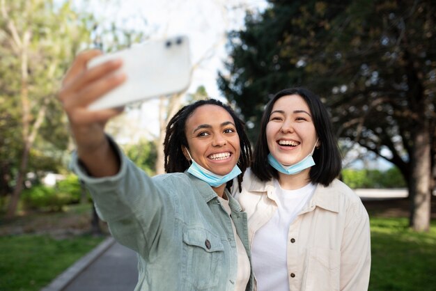 Medium shot smiley friends taking selfie in park