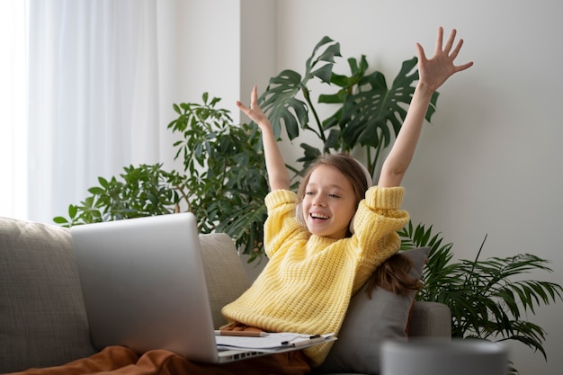 Medium shot smiley girl holding laptop