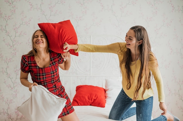 Free photo medium shot smiley girls in a pillow fight