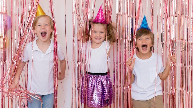 Free photo medium shot smiley kids wearing party hats