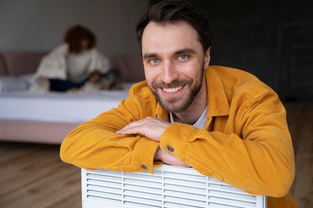 Medium shot smiley man at home with heater