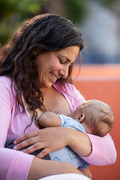 Medium shot smiley mother breastfeeding