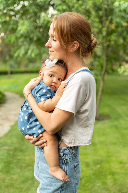 Free photo medium shot smiley mother holding baby