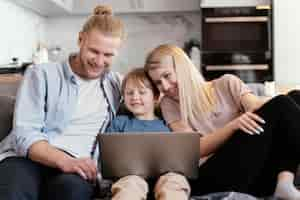 Free photo medium shot smiley parents and kid with laptop