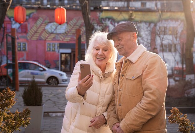 Medium shot smiley senior people holding phone