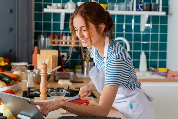 Free photo medium shot smiley woman cutting pepper