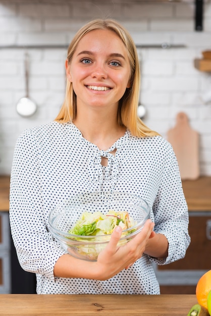 Free photo medium shot smiley woman holding bowl with salad