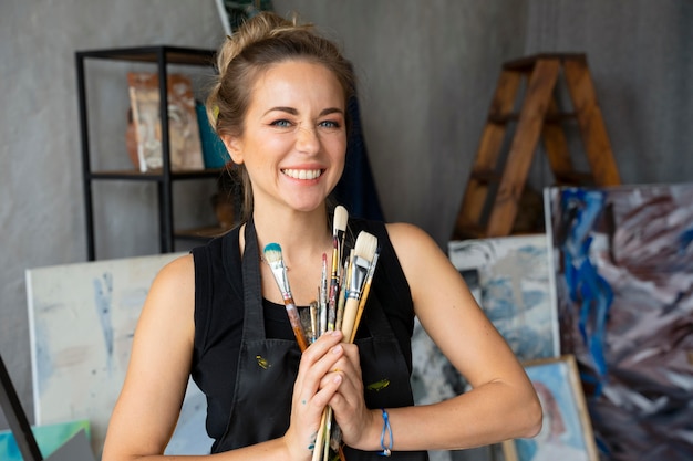 Free photo medium shot smiley woman holding different brushes