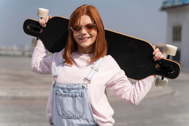 Medium shot smiley woman holding longboard