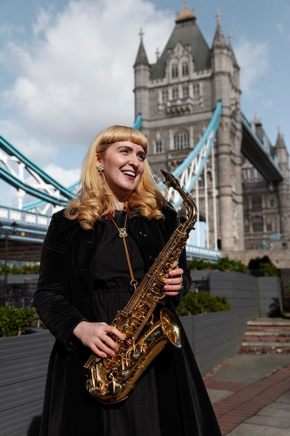 Free photo medium shot smiley woman holding saxophone