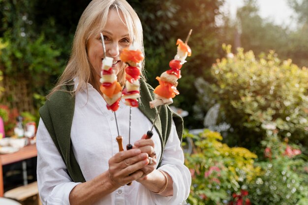 Medium shot smiley woman holding skewers