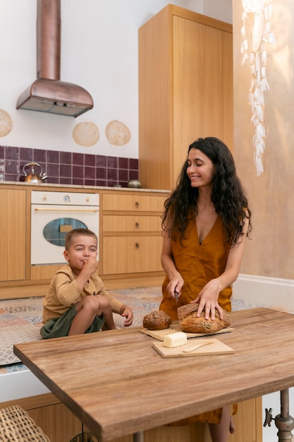 Free photo medium shot smiley woman and kid in kitchen