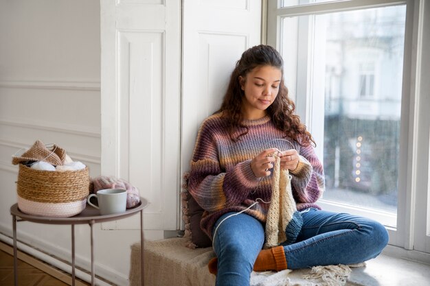 Medium shot smiley woman knitting at home