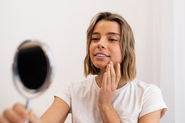 Free Photo medium shot smiley woman looking in the mirror