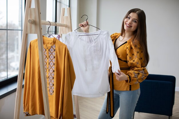 Medium shot smiley woman looking at ukranian shirt