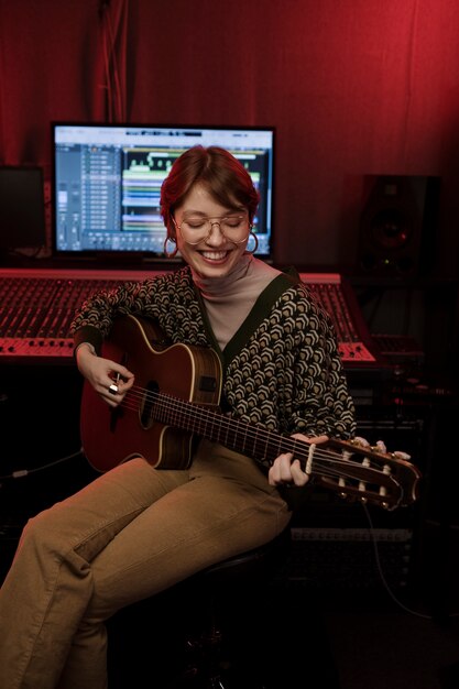 Medium shot smiley woman playing the guitar