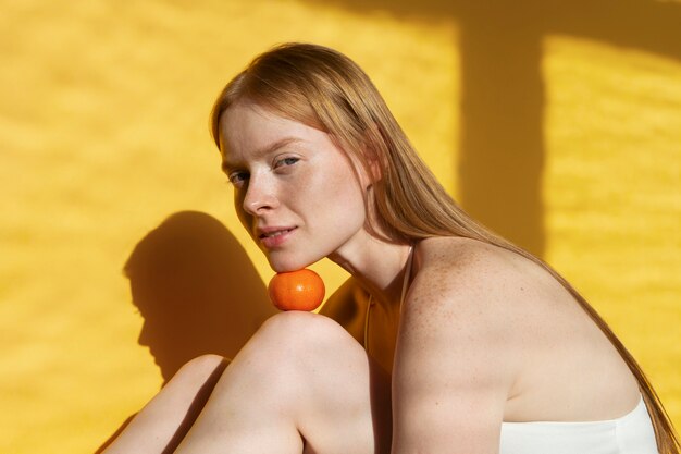 Medium shot smiley woman posing with tangerine