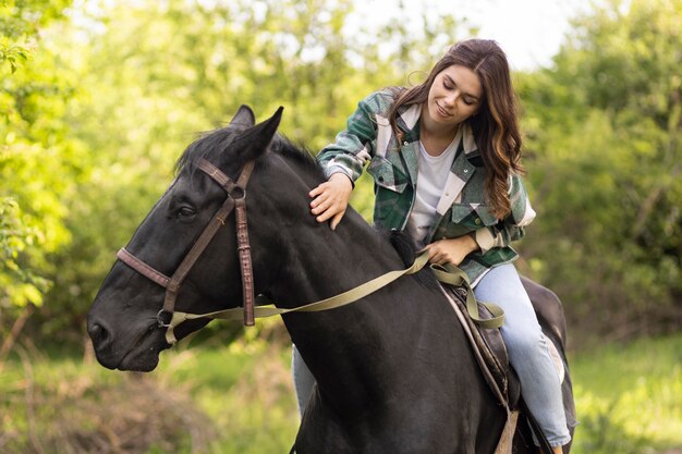 Medium shot smiley woman riding horse