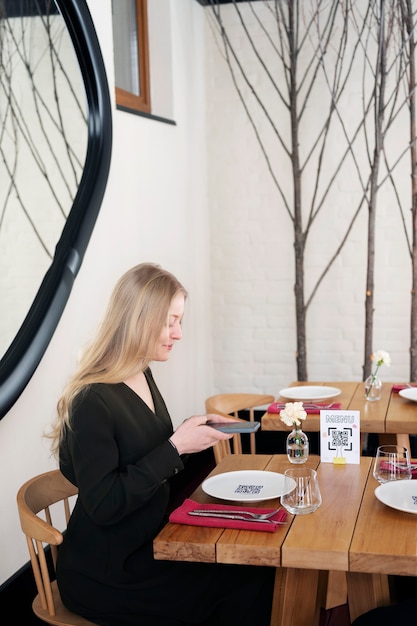 Medium shot smiley woman scanning qr at restaurant