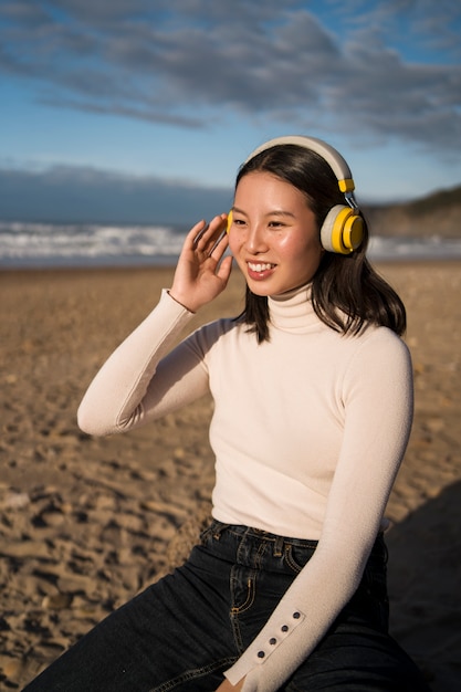 Free photo medium shot smiley woman sitting on beach