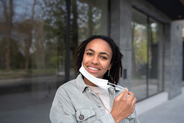 Free photo medium shot smiley woman taking face mask off