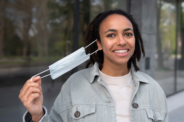 Medium shot smiley woman taking mask off outside