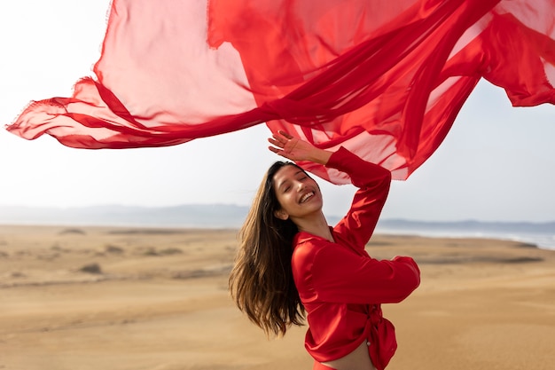 Free photo medium shot smiley woman throwing red scarf