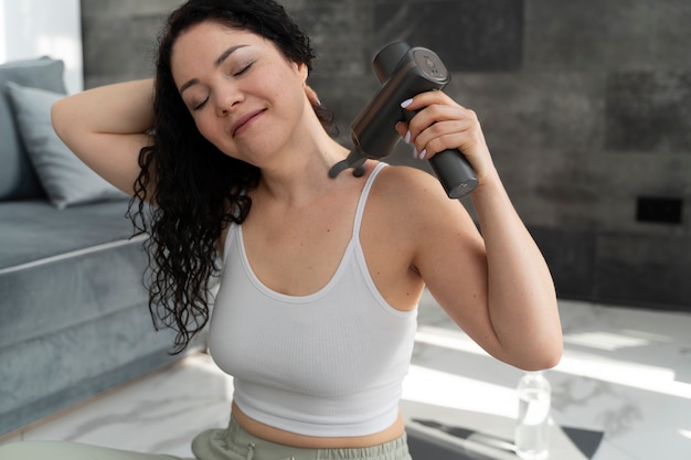 Free photo medium shot smiley woman using massage gun