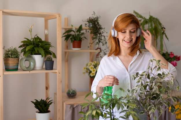 Medium shot smiley woman watering plant