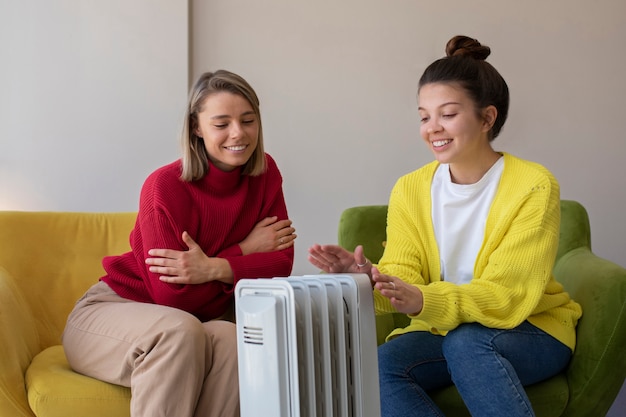 Medium shot smiley women getting warm near heater