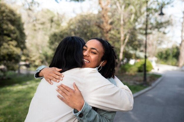 Medium shot smiley women hugging outdoors