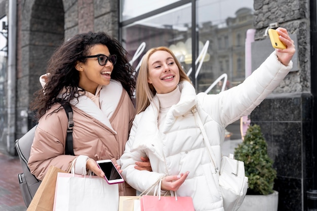 Medium shot smiley women taking selfie