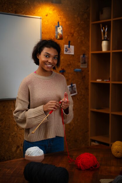 Medium shot smiley young woman knitting