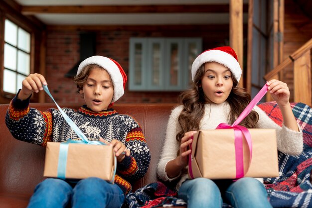 Medium shot surprised brother and sister opening gifts