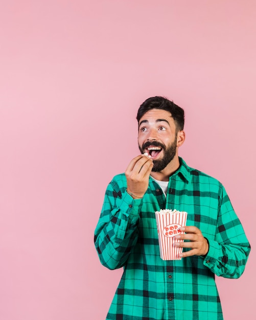 Free Photo medium shot surprised guy eating popcorn