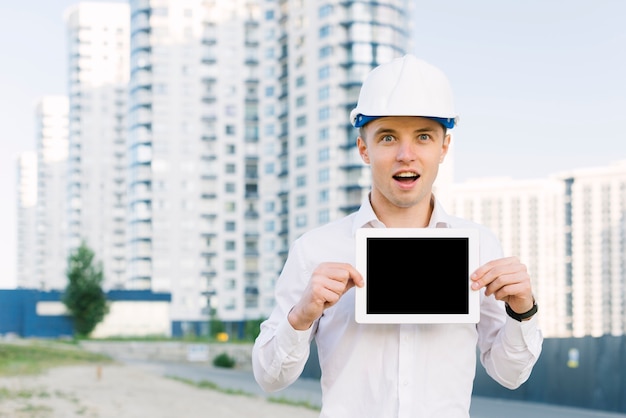 Free photo medium shot surprised man holding up tablet