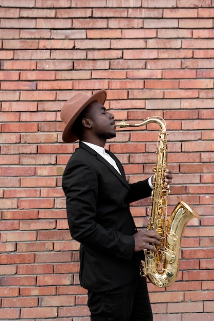 Free photo medium shot talented man playing saxophone