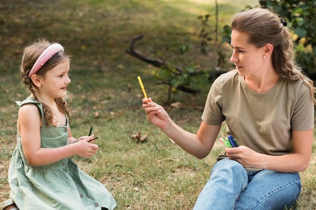 Free photo medium shot teacher and girl with crayons