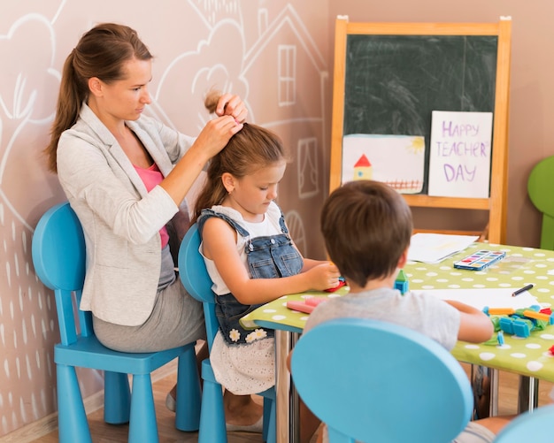 Medium shot teacher tying girl's hair