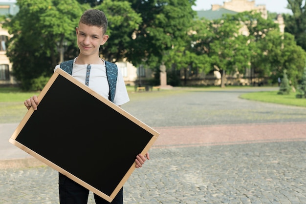 Free Photo medium shot teenage boy holding  black board