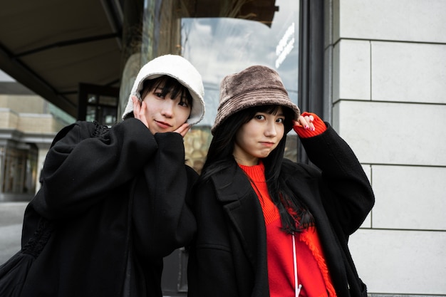 Medium shot trendy smiley women wearing hats