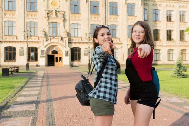 Medium shot of two highschool girls pointing at camera