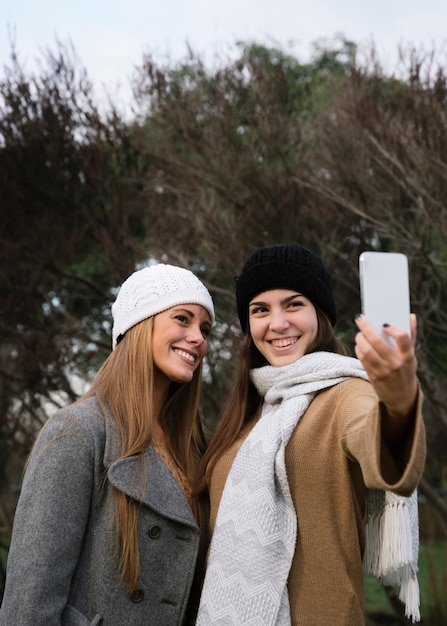 Medium shot two smiling women taking a selfie