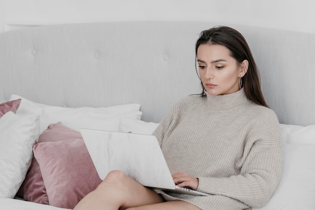 Medium shot woman in bed with laptop