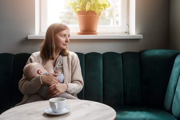 Medium shot woman breastfeeding baby indoors